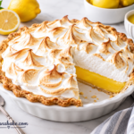 Slice of small lemon meringue pie with golden toasted meringue on a white plate